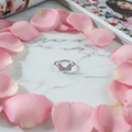 Anello Fiocco Pavé Argento su marmo con petali rosa