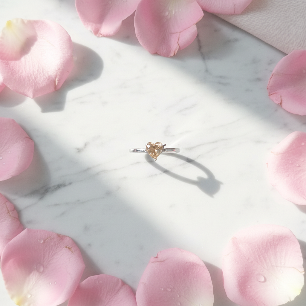 Anello Solitario Cuore Champagne su marmo con petali rosa