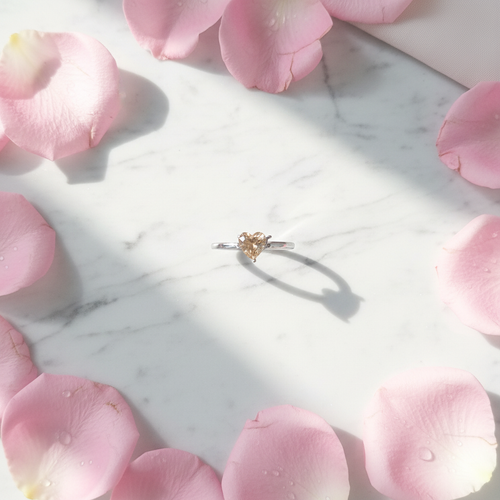 Anello Solitario Cuore Champagne su marmo con petali rosa